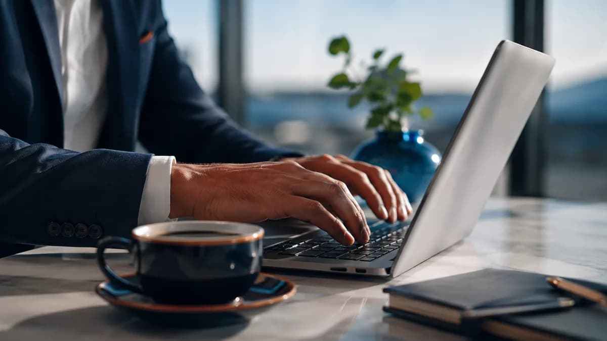 Hands on a computer keyboard with a cup of coffee, illustrating the writing of a refund email template